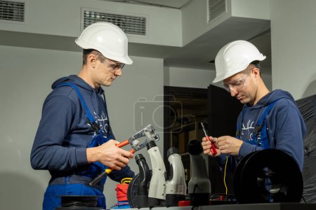 Photo for Electricians work in special equipped laboratory and install cables in charging plugs for electric cars. Technicians test cables and use pliers - Royalty Free Image