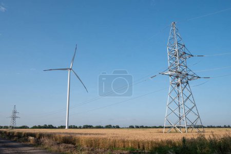 Photo for Windmill produces energy. Wind turbine supports row of power transmission lines with renewable and clean energy produced from natural source - Royalty Free Image