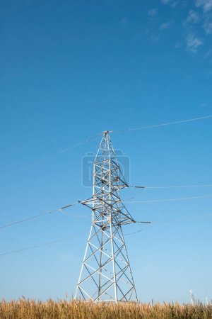 Photo for Power transmission line works from produced by windmill energy against blue sky. Transmission lines tower functions supported with electricity - Royalty Free Image