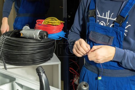 Photo for Technician works with cables for new charging plug for electric cars. Electrician connect wires and cables with charger for charging EV - Royalty Free Image