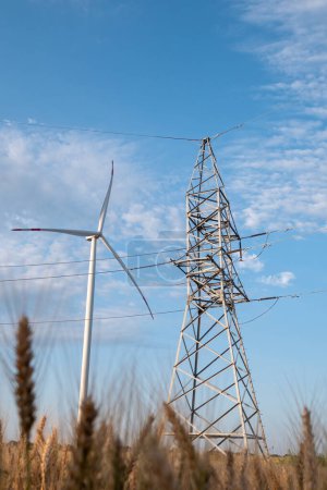 Foto de Molino de viento genera energía limpia. La torre de líneas de transmisión de energía funciona con energía de turbina eólica ecológica para un mejor funcionamiento y operación - Imagen libre de derechos