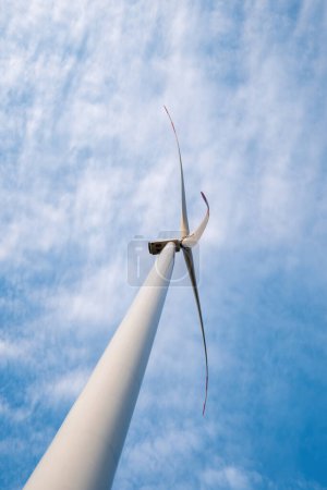 Foto de Ecofrieendly turbina eólica produce energía. Molino de viento genera energía alternativa para apoyar subestaciones y edificios con electricidad contra el cielo nublado - Imagen libre de derechos
