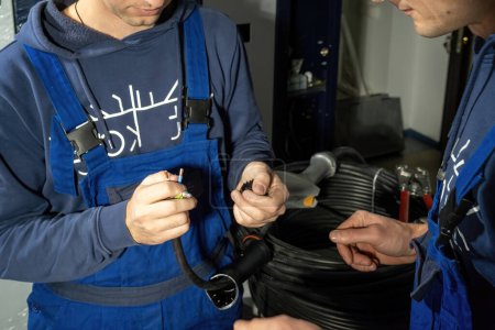 Photo for Technicians assemble cables and plug for charging EV on stations. Electricians try to improve charger with soldered cables in workshop - Royalty Free Image