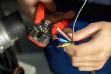 Téléchargez les photos : Ingénieur travaille avec des câbles pour brancher pour charger EV et utilise des pinces pour l'assemblage. Le contremaître vérifie la qualité des câbles et des travaux en atelier - en image libre de droit