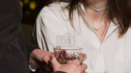 Photo for Young man vigorously gestures with clear glass in hand. Pleasant conversation with strong alcoholic cocktail in nightclub - Royalty Free Image