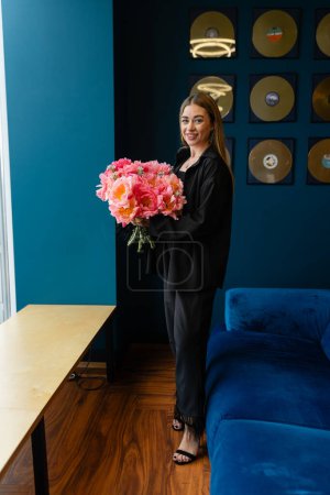 Photo for Blonde woman accepts flowers for successful completion of professional training program. Female employee receives bouquet from colleagues at workplace - Royalty Free Image