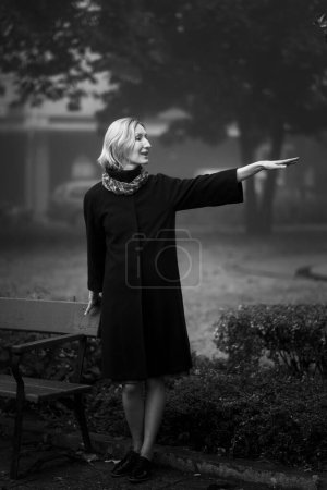 Foto de Una mujer saludando a conocidos de pie en la calle. Foto en blanco y negro. - Imagen libre de derechos