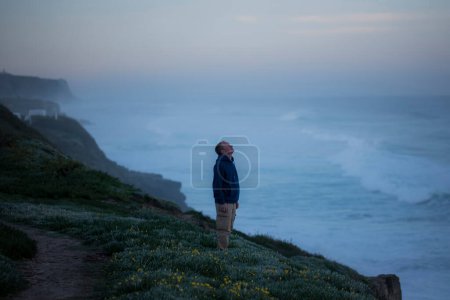 Ein Mann steht an der Atlantikküste vor dem Hintergrund der Morgenbrandung. 