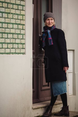 Foto de A woman on the porch of a house knocks on the door. - Imagen libre de derechos