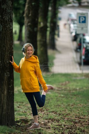 Photo for A woman worm-up in the city park before jog. - Royalty Free Image