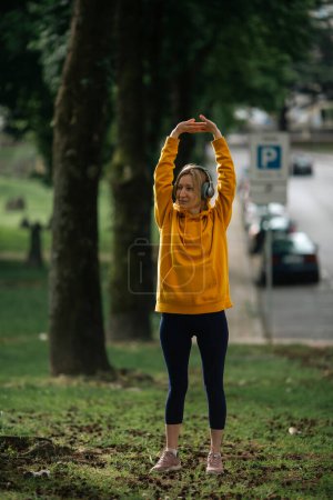 Photo for Woman wearing headphones exercises outdoor. - Royalty Free Image