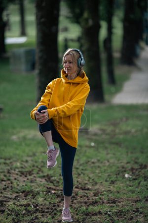 Photo for Woman wearing headphones exercises outdoor in the city Park. - Royalty Free Image