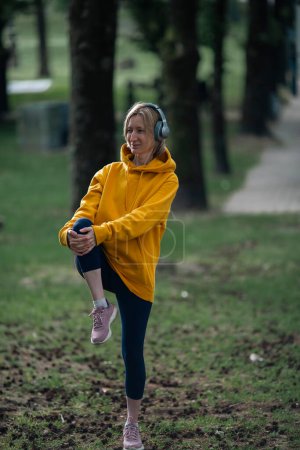 Photo for A woman wearing headphones warms up in the fresh air. - Royalty Free Image