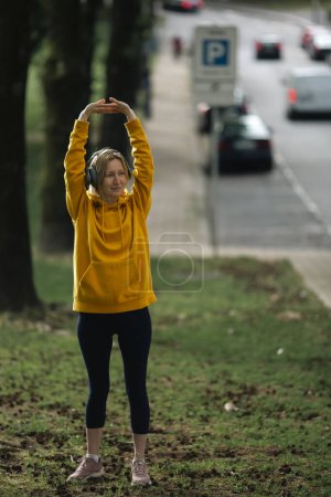 Photo for Woman wearing headphones exercises in the fresh air. - Royalty Free Image
