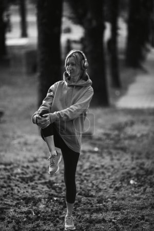 Photo for A woman wearing headphones exercises outdoors. Black and white photo. - Royalty Free Image
