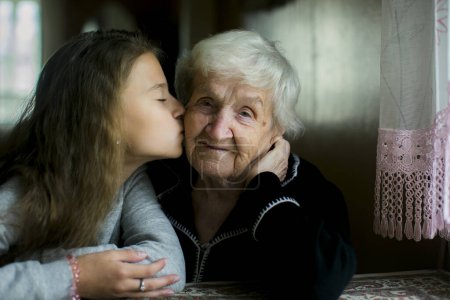 Photo for A teenage girl kisses her great-grandmother. - Royalty Free Image