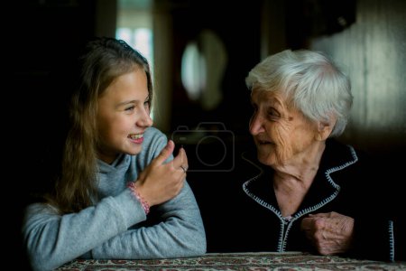 An old grandmother discusses with a little girl who laughs.