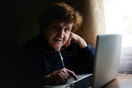 Eine ältere Frau beschäftigt sich mit Technik, ihre Finger tippen auf eine Laptop-Tastatur. Sie schlägt eine Brücke zwischen Tradition und Moderne und umarmt den digitalen Raum mit Weisheit.