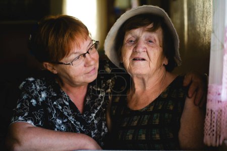 Foto de Una mujer mayor y su hija adulta se sientan juntas, sus expresiones transmiten toda una vida de amor, sabiduría y conexión. - Imagen libre de derechos