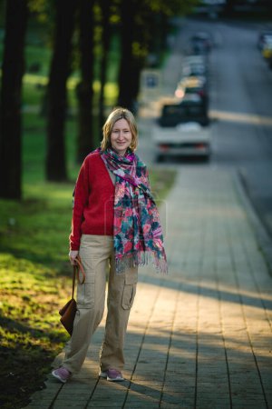 Un retrato de una mujer de mediana edad en un camino, exudando confianza y gracia en medio de los alrededores.