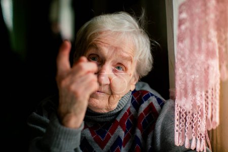 A close-up portrait of an elderly woman shaking her finger.