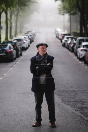 Un hombre de mediana edad con estilo paseando por un callejón de la ciudad brumosa.