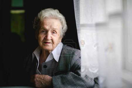 Une dame âgée pose pour un portrait, regardant directement la caméra avec grâce et dignité.