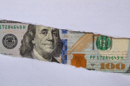 Billet de 100 dollars dans un trou de papier déchiré à des fins de conception