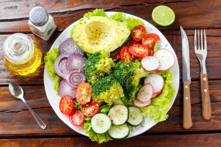 Frischer roher Gemüsesalat mit Tomaten, Avocado, Brokkoli, Zwiebeln, Rettich und Blumenkohl. Gesundes und entgiftendes Ernährungskonzept. Ketogene Ernährung. Grüner Salat. Ansicht von oben