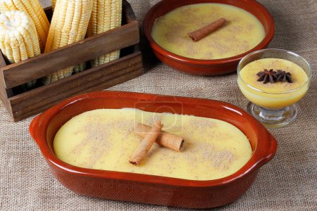Curau, süße Maiscreme und Dessert, typisch für die brasilianische Küche, in einer Keramikschüssel auf einem Holztisch. Nahaufnahme