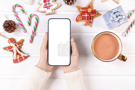 Photo for Close up woman holding smartphone with empty white screen mockup over decorated festive background, celebrating Christmas, customer shopping online, purchasing gifts, browsing gadget apps - Royalty Free Image