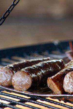 Photo for Sizzling sausage on a campfire at a barbecue event. - Royalty Free Image