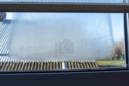 Nahaufnahme eines undichten Fensters im Innenraum. Kondenswasser am Fenster