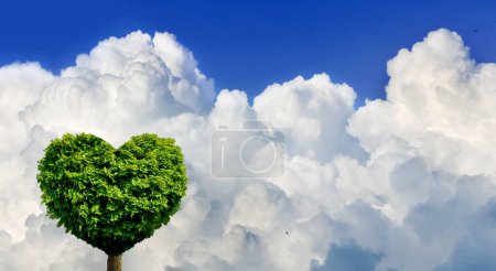 Foto de Una imagen de un árbol cuya copa parece un corazón sobre el fondo de nubes blancas y un cielo azul - Imagen libre de derechos