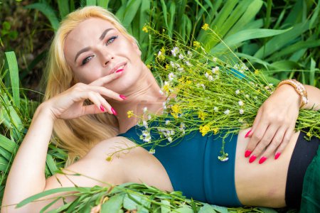 Téléchargez les photos : Belle mannequin blonde de mode profitant de la nature, respirant l'air frais dans le jardin d'été sur fond de feuilles vertes. Concept d'harmonie - en image libre de droit