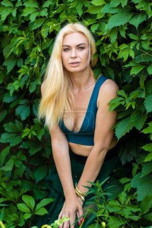 Photo for Beautiful fashion blonde model enjoying nature, breathing fresh air in summer garden over green leaves background. Harmony concept - Royalty Free Image