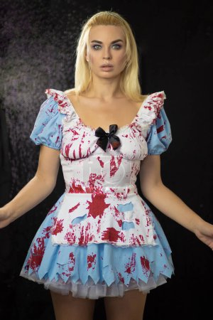 Foto de Hermosa joven rubia con un traje de Alice. El vestido está desgarrado y manchado con sangre falsa. Concepto de Halloween. Enfoque suave - Imagen libre de derechos