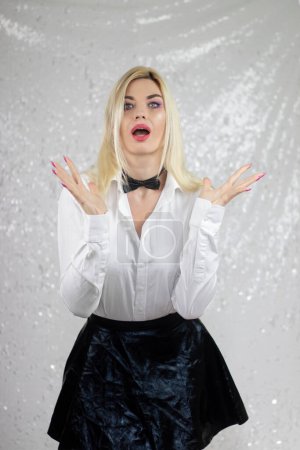 Photo for Fashion blonde model woman in white shirt and black skirt with bow tie, in the style of gothic pop surrealism, light gray and white background, xmaspunk, silver and black, crumpled - Royalty Free Image