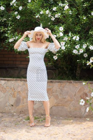 Old Hollywood Glam: Beautiful Woman in Polka Dot Dress by Bushes