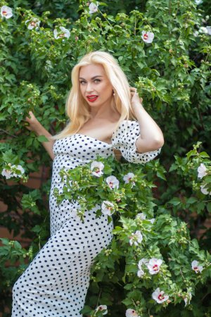 Photo for Garden Glamour: Blonde Woman in Polka Dot Ensemble - Royalty Free Image