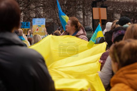 Photo for Dublin, Co. Dublin, Ireland - February 24th 2023 - Ukrainians and supporters rally. The first anniversary of Russia's invasion of Ukraine. O'Connell street near GPO. Woman holding Ukrainian flag - Royalty Free Image