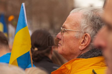Photo for Dublin, Co. Dublin, Ireland - February 24th 2023 - Ukrainians and supporters rally. The first anniversary of Russia's invasion of Ukraine. O'Connell street near GPO. Close up of old man holding flag - Royalty Free Image