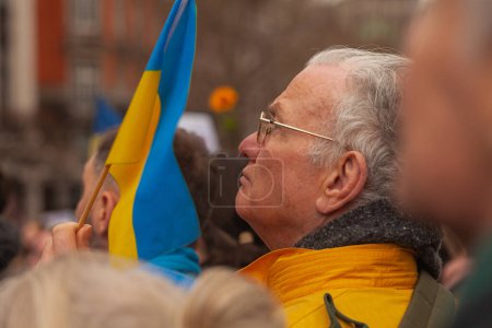 Foto de Dublín, Co. Dublín, Irlanda - 24 de febrero de 2023 - Manifestación de ucranianos y simpatizantes. El primer aniversario de la invasión rusa de Ucrania. Calle O 'Connell cerca de GPO. Anciano sosteniendo bandera - Imagen libre de derechos