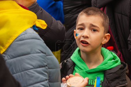 Photo for Dublin, Co. Dublin, Ireland - February 24th 2023 - Ukrainians and supporters rally. The first anniversary of Russia's invasion of Ukraine. O'Connell street near GPO. A boy with painted cheek - Royalty Free Image