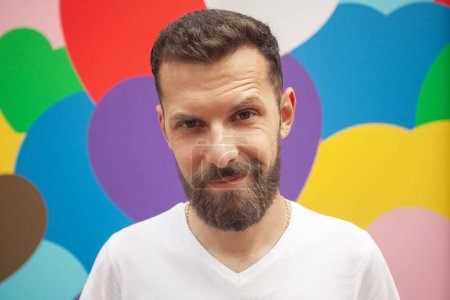 Photo for Love concept. Portrait of proud charismatic active 30-year-old man posing over colourful background. Perfect haircut. Hipster style. Close up. Outdoor shot - Royalty Free Image