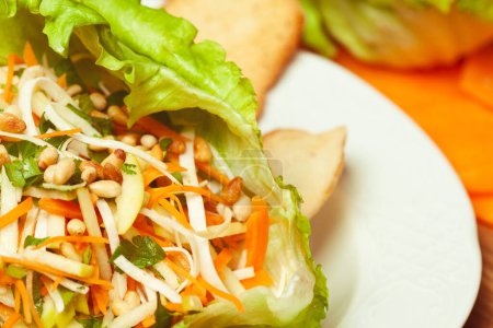 Photo for Vegan cuisine, healthy food concept. Fresh delicious vegetable salad - mix of celeriac, carrot, apple, iceberg lettuce and pine nut. Close up. Indoor shot - Royalty Free Image