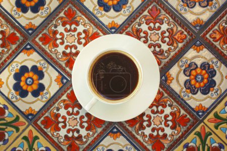 Photo for Cup of tasty black coffee on round table made of beautiful ceramic tiles. Turkish style. Close up. Flat layout. Outdoor shot - Royalty Free Image