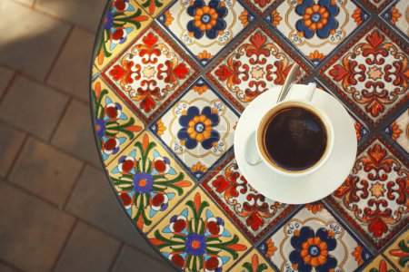 Foto de Copa de sabroso café negro en mesa redonda hecha de hermosas baldosas de cerámica. Estilo turco. De cerca. Disposición plana. Espacio de texto. tiro al aire libre - Imagen libre de derechos