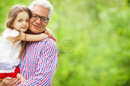 Photo for Family values concept. Portrait of stylish and fashionable grandfather with his grandchild sitting in his hands. Close up. Copy-space. Outdoor shot - Royalty Free Image