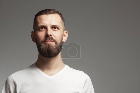 Foto de Male beauty concept. Portrait of proud charismatic active 30-year-old man posing over gray background. Perfect haircut. Hipster style. Copy-space. Close up. Studio shot - Imagen libre de derechos
